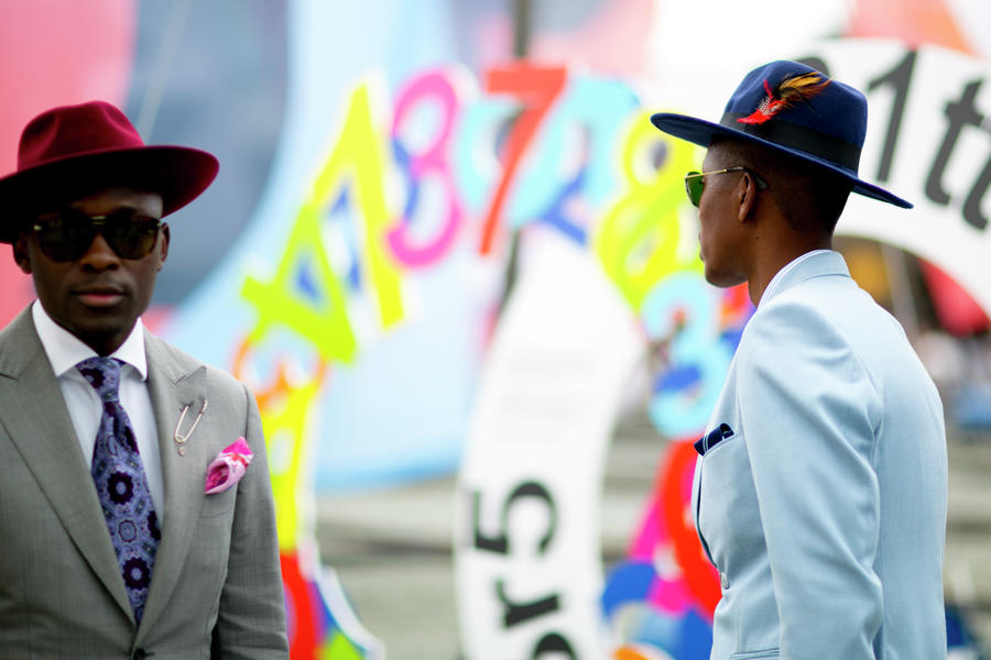 Fedora Two men wear a gray (left) and light blue (right) suits and red (left) and blue (right) fedora
