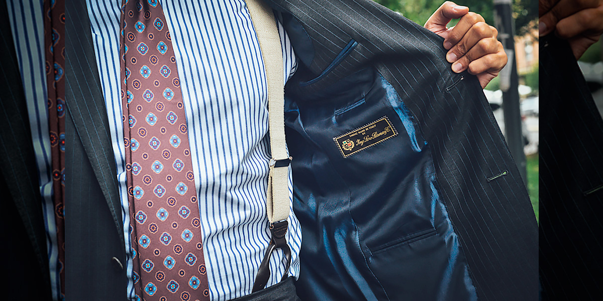 Uomo indossa un completo elegante grigio su misura con tessuto Loro Piana