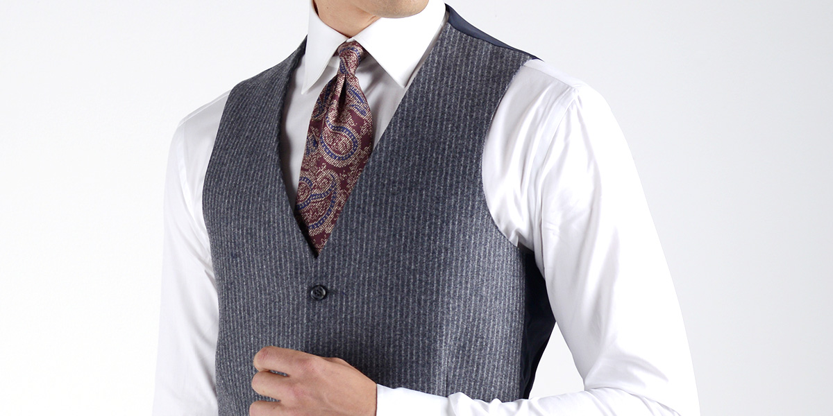 Panciotto grigio gessato indossato su camicia bianca e cravatta bordeaux fantasia
