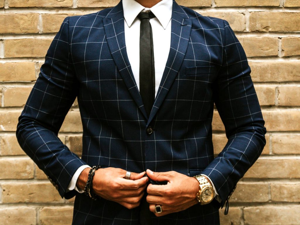 Un uomo si appresta ad abbottonare l'ultimo bottone della sua giacca